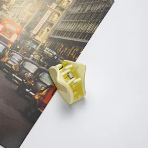 Detail of a creamy yellow mini hair claw clip with a strong silver metal spring and smooth edges