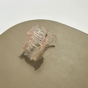 Detailed close-up of a pink heart-shaped translucent hair claw clip on a textured display