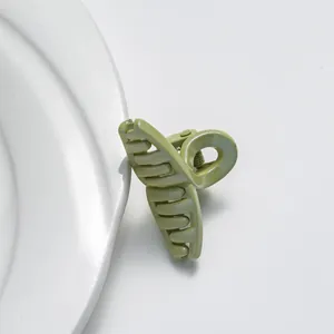 Mini pince à cheveux vert clair avec paillettes et texture givrée sur assiette blanche