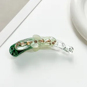 Gros plan détaillé sur un clip banane vert clair orné de fleurs en strass étincelants
