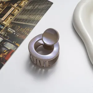 Close-up of 3.5cm round hair claw clip with blue-purple glitter finish on cream tray
