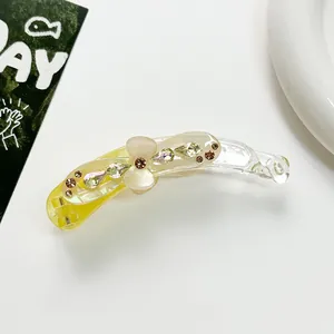 Détail de pince à cheveux banane avec strass et fleur translucide sur fond blanc pur
