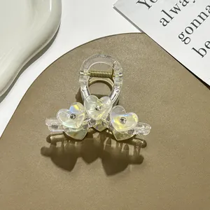 Detail of pearlescent heart hair claw clip with rhinestones and golden metal spring