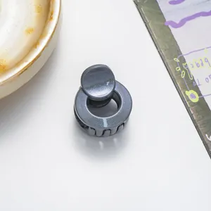 Detail of mini round hair claw clip with glitter finish next to a coffee cup