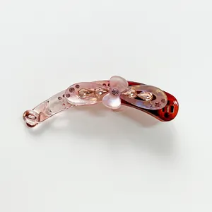 Détail d'une pince banane dégradée avec strass roses et une fleur de perle centrale