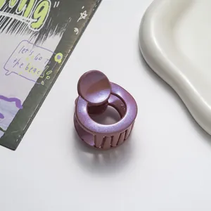Detail of round pearlescent purple hair claw clip with glitter finish on a white background