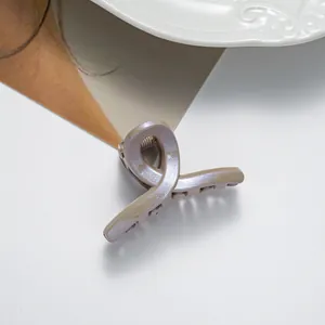 Gros plan d'une mini pince à cheveux champagne pailletée avec un design ruban torsadé