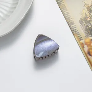 Macro detail of triangle cat ear hair clip with purple glitter finish on light surface