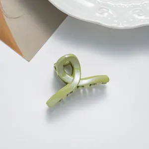 Détail d'une petite pince à cheveux vert menthe pailletée sur une assiette décorative en porcelaine