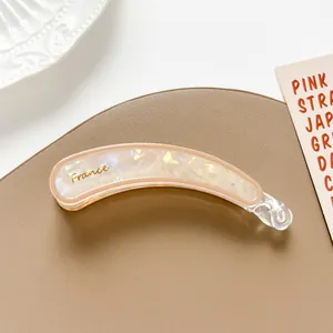 Detalle de pinza de pelo tipo banana con textura de mármol iridiscente y letras de France