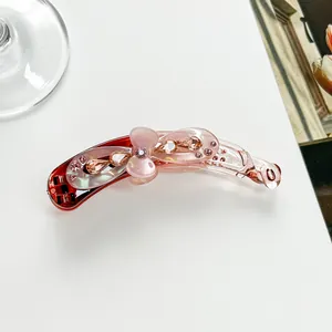 Détail d'une barrette banane rose en résine avec cristaux et décoration florale