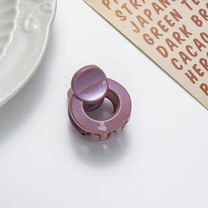 Detail of a mini round glitter hair claw clip with a shimmering metallic rose finish