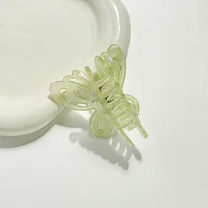 Macro shot of light green translucent butterfly hair claw clip on white ceramic tray