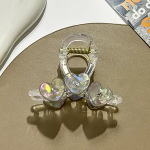 Macro detail of transparent hair claw with iridescent hearts and sparkling rhinestones