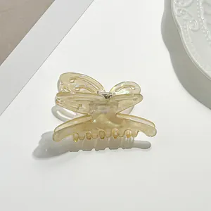Detail of a butterfly-shaped cream resin hair claw clip with pearlescent finish and metal spring