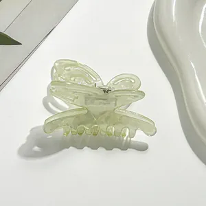 Detail view of a translucent light green butterfly hair claw clip with a silver spring