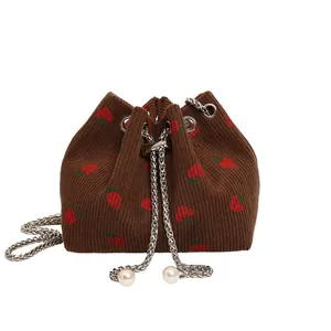Brown strawberry drawstring bucket bag with corduroy texture and pearl chain strap