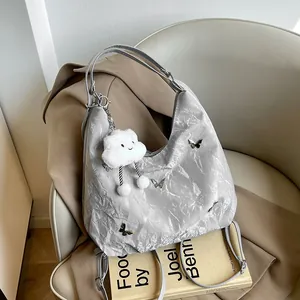 Silver pleated shoulder bag with metal butterfly and white cloud pendant on a chair