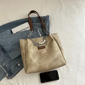 Vintage light brown tote bag with chain strap and pearl detail on white cloth