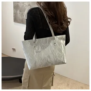 Macro detail of the silver tote bag showing pleated texture and metallic finish