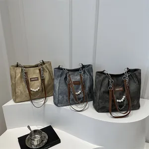 Three retro chain shoulder bags in khaki and grey, styled with pearls and book props