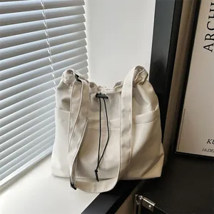 Minimalist off-white oversized tote bag with drawstring closure and dual shoulder straps