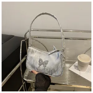 Detail of silver metallic butterfly buckle and pleated fabric on stylish shoulder bag