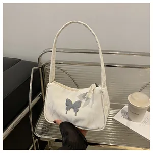 Detail of cream white underarm bag with a liquid metal butterfly logo on textured leather