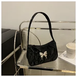 Close-up of black pleated fabric shoulder bag with large silver butterfly buckle detail