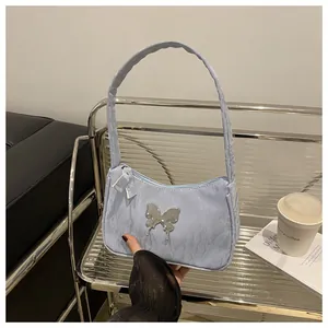 Detail of light blue pleated fabric handbag with silver butterfly clasp and zipper pull