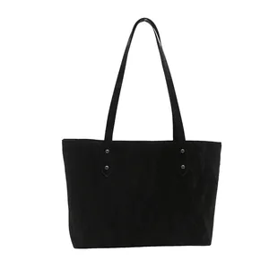 Minimalist black tote bag with matte texture, silver rivets and long shoulder straps
