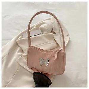 Close-up of pink pleated fabric underarm bag with silver butterfly emblem on beige blazer
