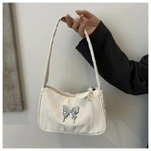 Detail of white vintage shoulder bag with metallic butterfly buckle and textured fabric