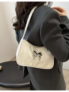 Fashionable cream butterfly shoulder bag styled with a gray blazer for a modern look