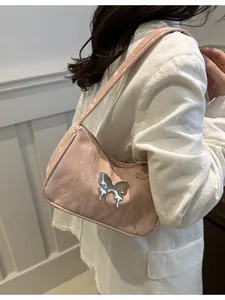 Pink butterfly shoulder bag with liquid metal Y2K charm on a model in white blazer