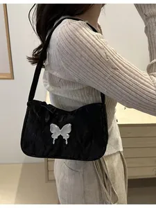 Fashionable black butterfly underarm bag shown on model with silver metal buckle detail
