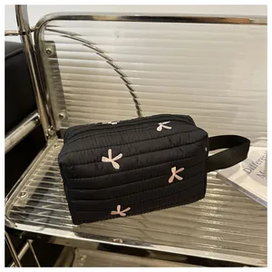 Detail of black quilted pouch with pink bow embroidery and durable metal zipper