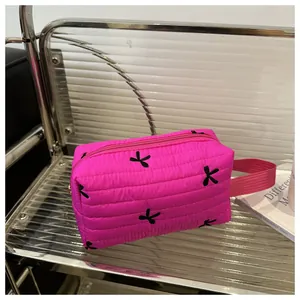 Close-up of quilted fuchsia cosmetic bag featuring bow patterns and metal zipper