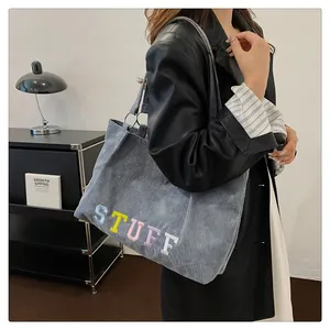 Detailed view of the corduroy tote bag with embroidered letters and comfortable wide strap