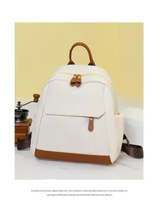 Detail of white Oxford backpack featuring brown leather accents and gold hardware details