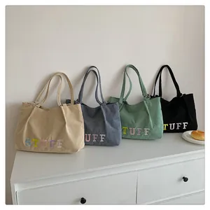 Detailed row of corduroy tote bags with STUFF letter embroidery in four soft colors