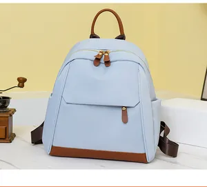 Close-up of light blue Oxford backpack with brown leather details and side pocket detail