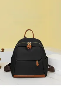 Detail of black oxford backpack with brown leather accents and front zipper pocket