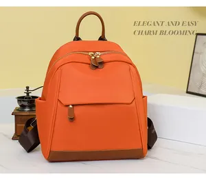 Detail view of orange nylon travel backpack with brown leather handles and side pockets