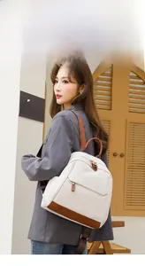 Outdoor model view of beige oxford cloth commuter backpack with brown leather accents