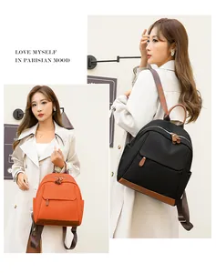 Detail of stylish nylon backpacks in black and orange with brown leather accents