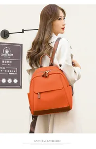 Detail of orange nylon commuter backpack with brown leather trim and gold hardware