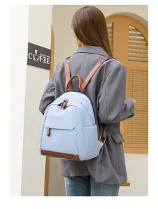 Light blue nylon commuter backpack featuring brown leather trim detail shown from a back view