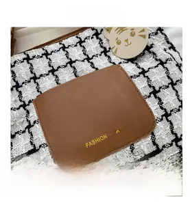 Détail de sac en pied-de-poule avec poche en similicuir marron et logo doré élégant