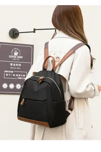 Urban black nylon backpack with brown leather trim shown on model in street setting